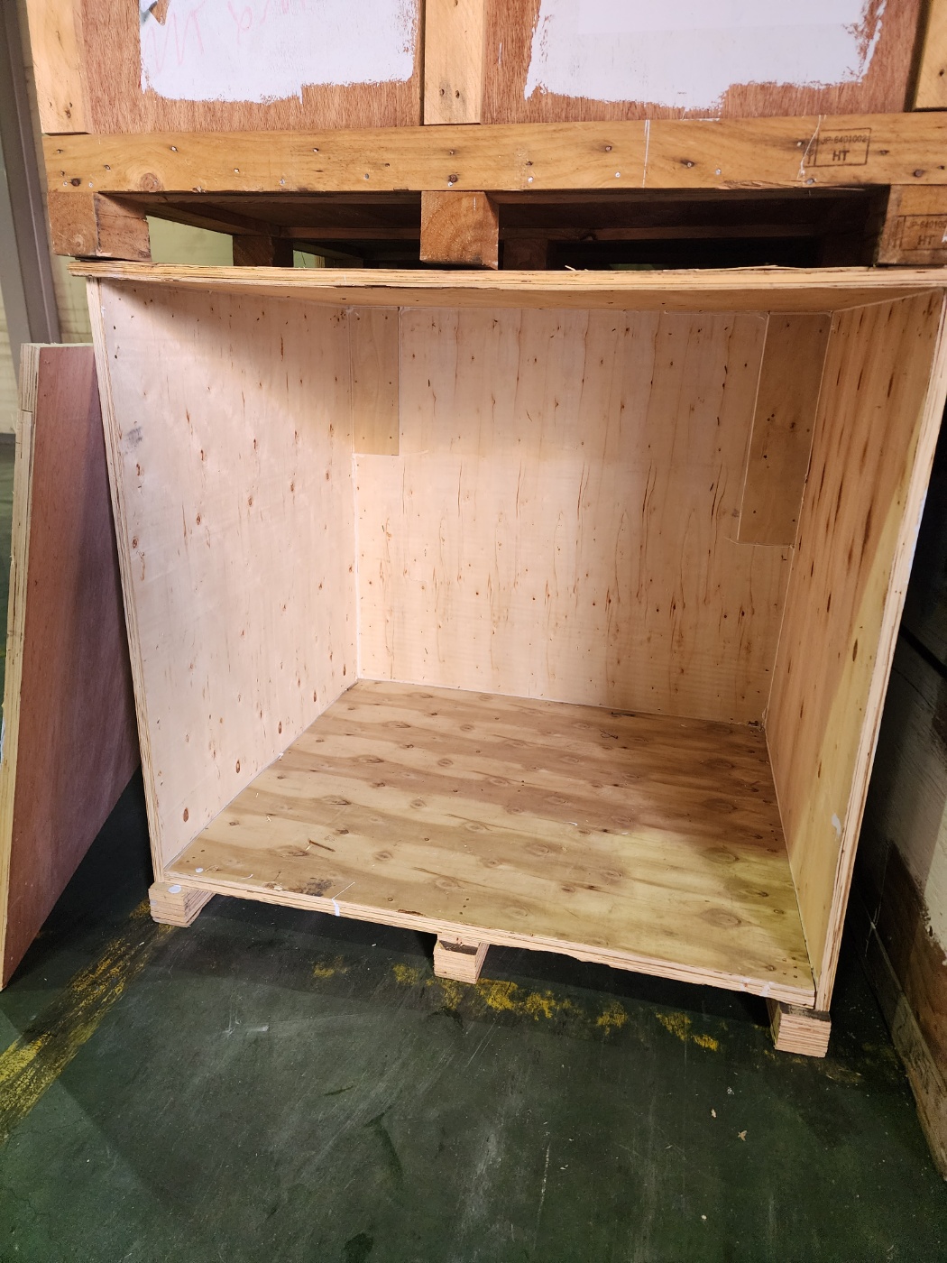 The interior of an empty wooden storage crate on a warehouse floor